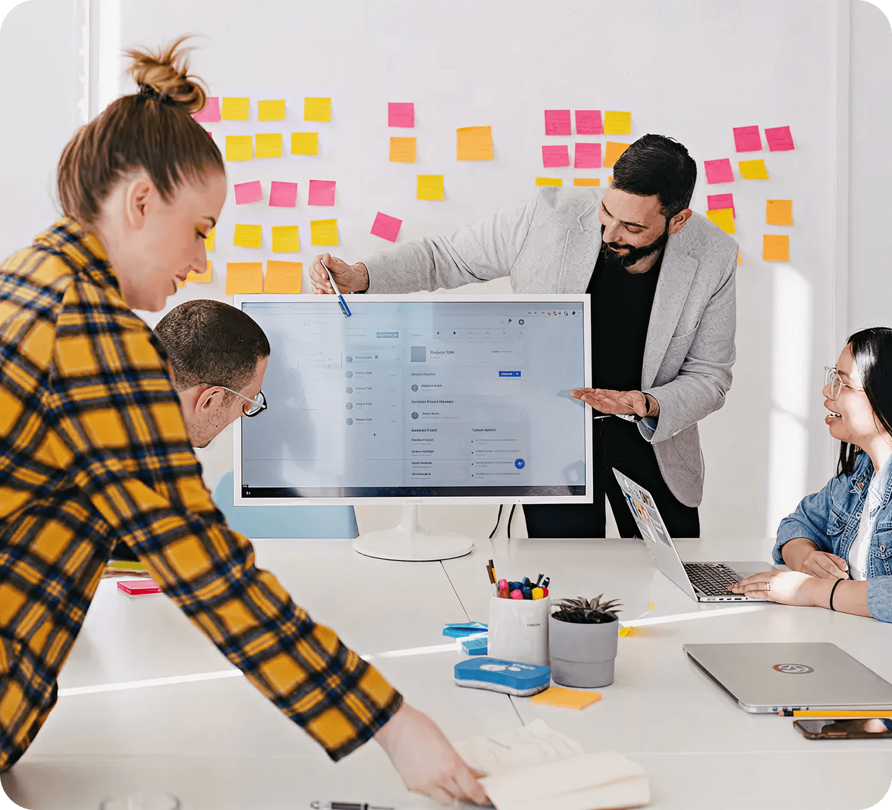 Team collaborating around a desk with sticky notes and a monitor