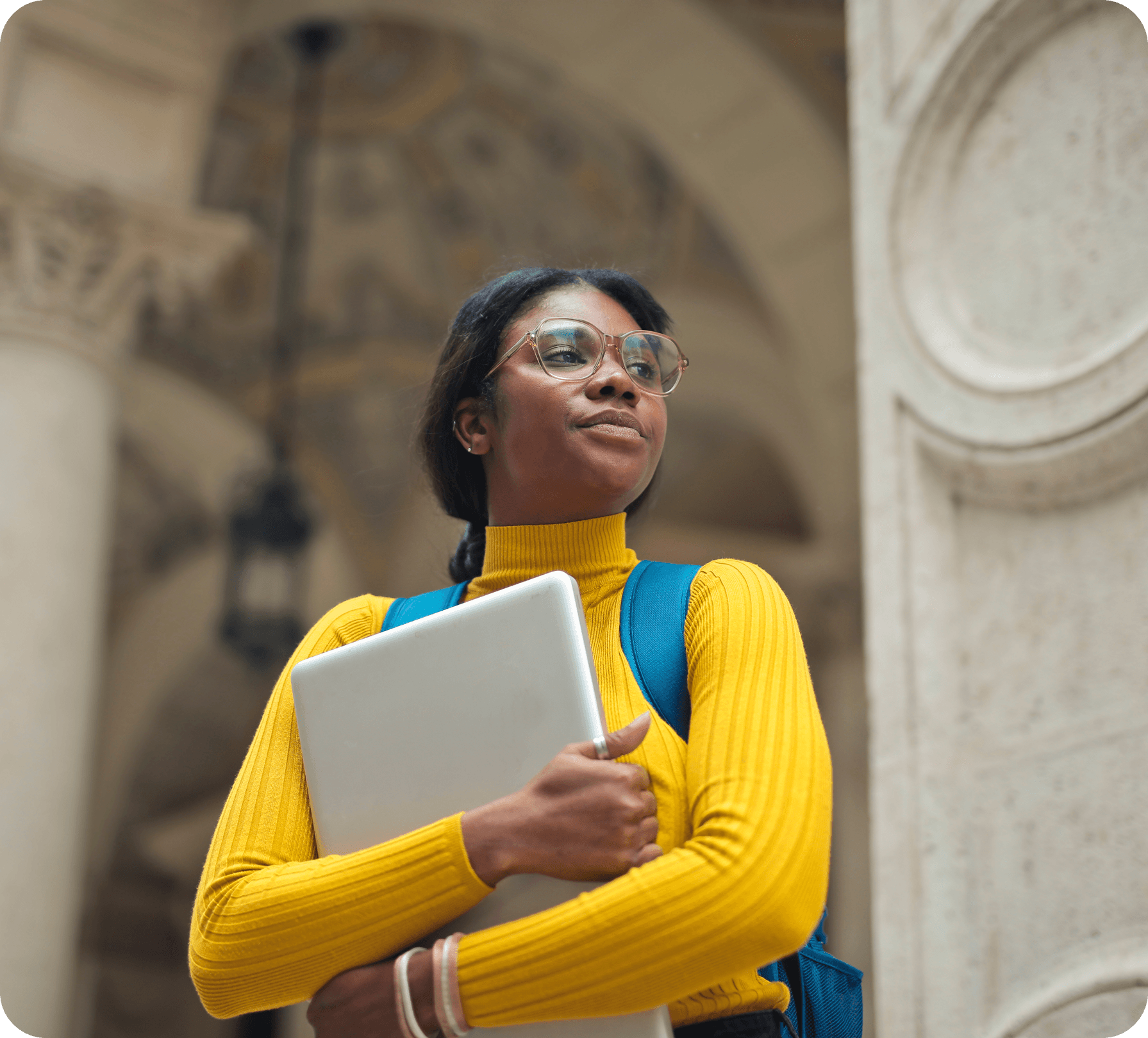 Student holding a laptop looking up thoughtfully